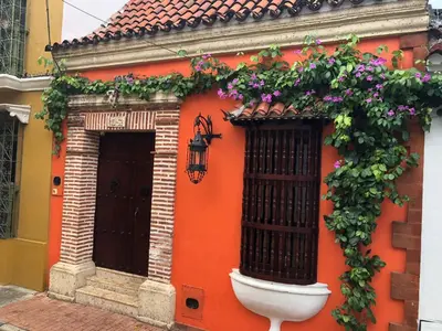 an orange building with flowers on the side of it at Luxury Colonial Villa Old City Cartagena Rooftop Views Private Pool in Cartagena de Indias