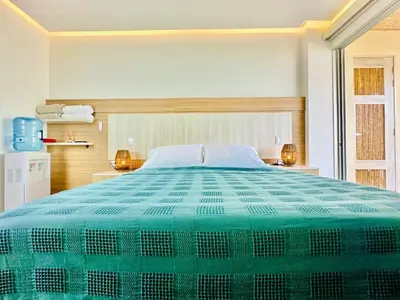 a bedroom with a large bed with a green comforter at Aves de Laguna Beach in Trementino