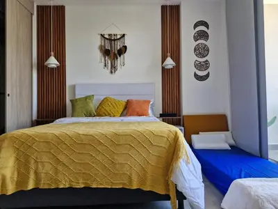 a bedroom with a bed with a yellow blanket at Modern suite steps from the sea in Santa Marta