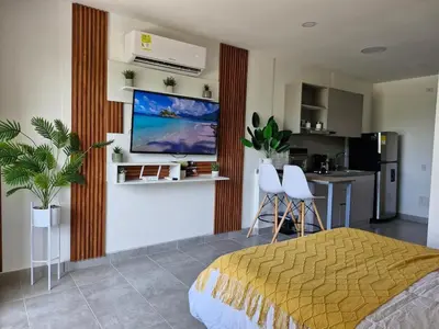 a bedroom with a bed and a tv on a wall at Modern suite steps from the sea in Santa Marta