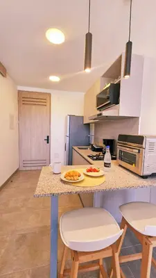 a kitchen with a counter with two stools and a table at 1BD Luxe Shore & Balcony Sunrise Next to the Beach in Santa Marta