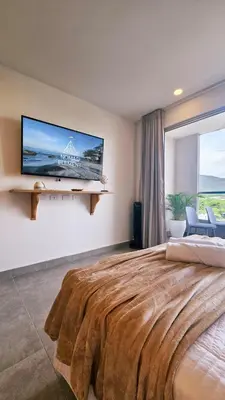 a bedroom with a large bed with a tv on the wall at 1BD Luxe Shore & Balcony Sunrise Next to the Beach in Santa Marta