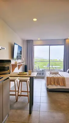 a bedroom with a bed and a kitchen with a view at 1BD Luxe Shore & Balcony Sunrise Next to the Beach in Santa Marta