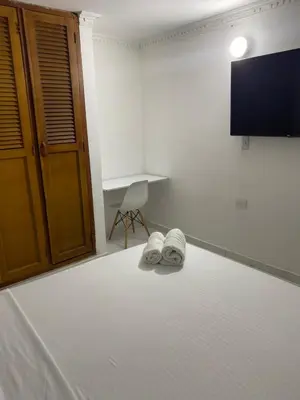 a bedroom with a bed with a tv and two slippers at Habitación cerca al aeropuerto # 5 in Cartagena de Indias