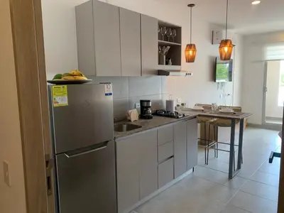 a kitchen with white cabinets and a stainless steel refrigerator at Apartamento Playa y piscina, Santa Marta in Santa Marta