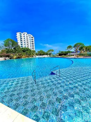 a swimming pool with blue water and a tall building at Anny Luxury Apartment - Santa Marina in Santa Marta