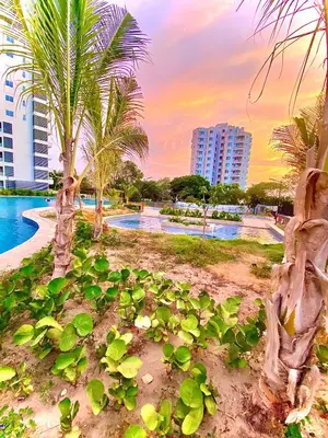 a resort with a pool and palm trees and a building at Anny Luxury Apartment - Santa Marina in Santa Marta