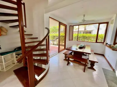 a living room with a wooden staircase and a table at Hermosa villa frente al mar in San Silvestre