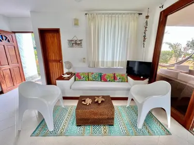 a living room with a white couch and two white chairs at Hermosa villa frente al mar in San Silvestre