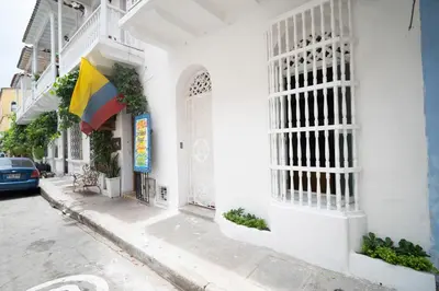 a white building with a flag on a street at Alma Blanca - Colonial Loft in the Walled City in Cartagena de Indias