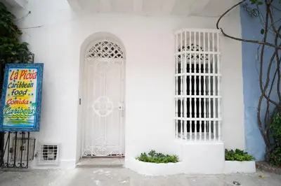 a white building with a white door and a sign at Alma Blanca - Colonial Loft in the Walled City in Cartagena de Indias