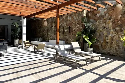 a patio with white chairs and a stone wall at Ultimo piso, amplia terraza y vista impresionante! in Los Arrayanes
