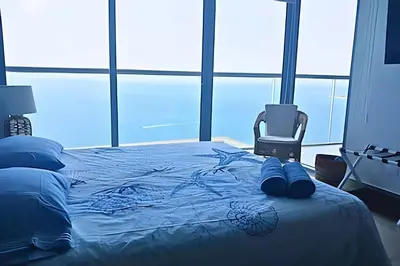 a bedroom with a bed with blue sheets and a chair at Luxury Escape: Sea, Comfort & Style in Cartagena de Indias