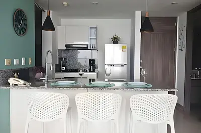 a kitchen with a counter with white chairs in it at Luxury Escape: Sea, Comfort & Style in Cartagena de Indias
