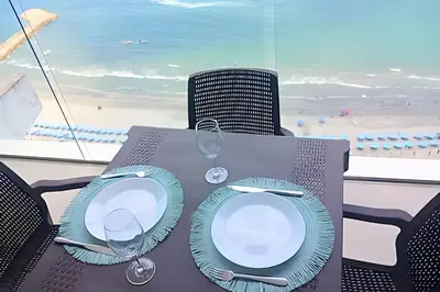 a table with two plates and wine glasses on a beach at Luxury Escape: Sea, Comfort & Style in Cartagena de Indias