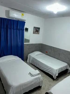 a room with two beds and a blue curtain at Hoteles & Restaurantes Doña Nerta in Cartagena de Indias