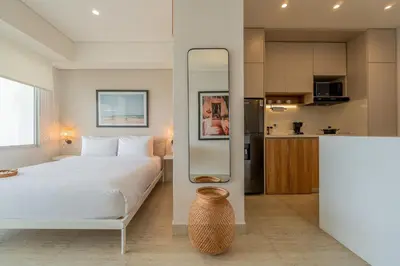 a bedroom with a large white bed and a kitchen at CB1515 | Lujosa suite con vista al mar y balcón in Cartagena de Indias