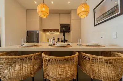 a kitchen with a bar with rattan chairs at CB1515 | Lujosa suite con vista al mar y balcón in Cartagena de Indias