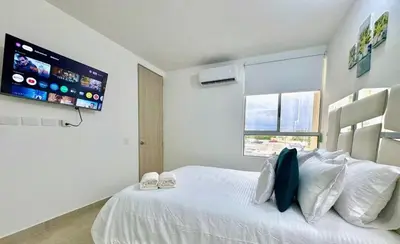 a bedroom with a white bed and a flat screen tv at Lindo apartamento a 5 minutos del mar!!! in Manzanillo del Mar