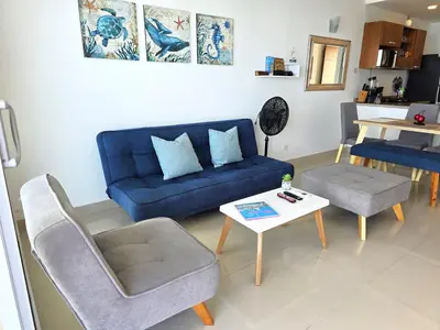 a living room with a blue couch and a table at Ikigai frente al mar con piscina infinita y Gym in Cartagena de Indias