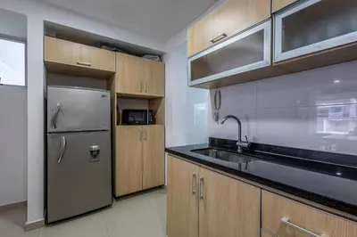 a kitchen with wooden cabinets and a stainless steel refrigerator at Morros Malibu Beach - Con vista al mar in Cartagena de Indias
