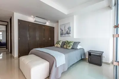 a bedroom with a large bed and a stool at Morros Malibu Beach - Con vista al mar in Cartagena de Indias