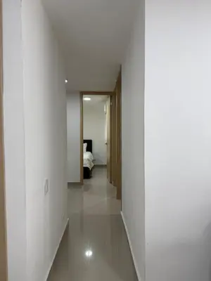 a hallway with white walls and a bed in a room at Apartamento moderno para rentar por Días - Nuevo in Barranquilla