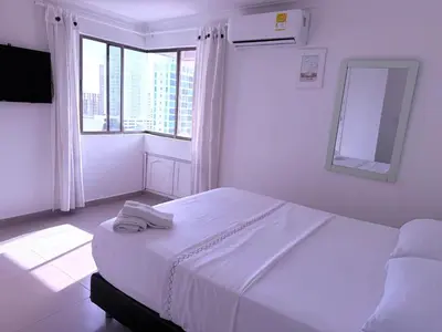 a white bedroom with a large bed and a window at Ocean view apartment in a great location in Cartagena de Indias