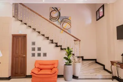 an orange chair in a living room with stairs at Hotel Paseo Colon in Barranquilla