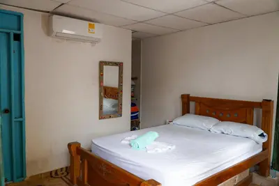 a bedroom with a bed with white sheets and a mirror at Cabaña las Palmas Rincon del Mar in Rincón