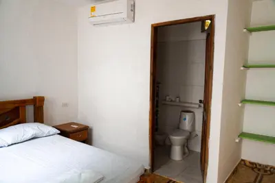 a bedroom with a bed and a bathroom with a toilet at Cabaña las Palmas Rincon del Mar in Rincón