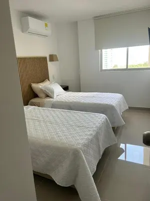 two beds in a white bedroom with a window at Vicmag House Barranquilla in Barranquilla