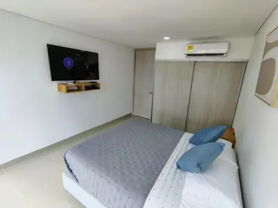 a bedroom with a bed with blue pillows and a tv at Apartamento en Edificio Magno Loft Apto DP 1001 in Cartagena de Indias