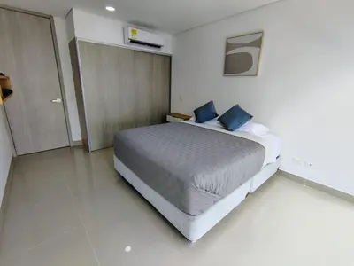 a bedroom with a large bed with blue pillows at Apartamento en Edificio Magno Loft Apto DP 1001 in Cartagena de Indias