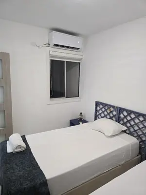 a white bedroom with a bed and a window at Apartamento Cerca al Mar Cartagena in Cartagena de Indias