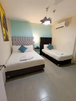 a bedroom with two beds with blue pillows at Art Hotel Getsemani in Cartagena de Indias