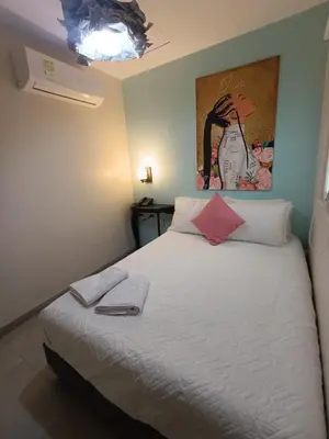 a bedroom with a white bed with a painting on the wall at Art Hotel Getsemani in Cartagena de Indias