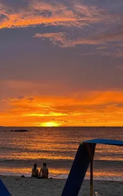two people sitting on the beach watching the sunset at Apartamento con vistas al Mar caribe in Coveñas