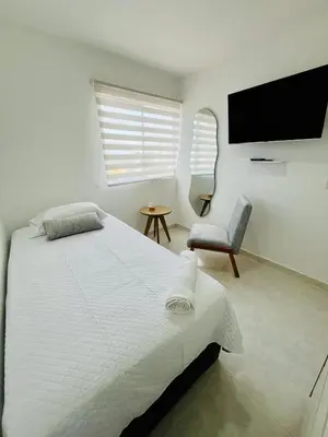 a white bedroom with a bed and a chair at Beach Nearby Stunning Views Ultimate Comfort in Cartagena de Indias