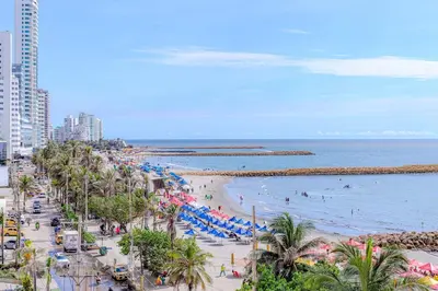 a beach with people and umbrellas and the ocean at Spacious beachfront apartment in Cartagena de Indias