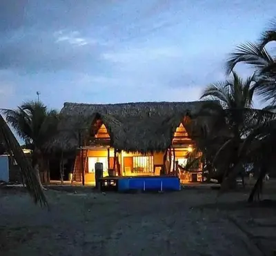 a house with a thatched roof with palm trees at Coco y arena cabaña frente al mar, lejos del turismo y cerca a los manglares in San Bernardo del Viento