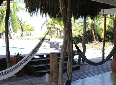 a hammock on a deck next to a beach at Coco y arena cabaña frente al mar, lejos del turismo y cerca a los manglares in San Bernardo del Viento