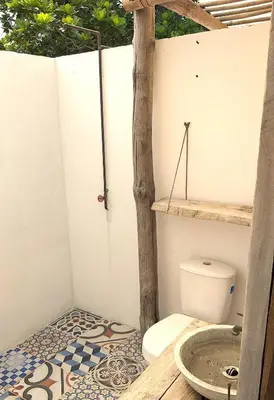 a bathroom with a toilet with a tree in it at Coco y arena cabaña frente al mar, lejos del turismo y cerca a los manglares in San Bernardo del Viento