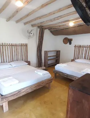 a room with two beds and a table at Coco y arena cabaña frente al mar, lejos del turismo y cerca a los manglares in San Bernardo del Viento