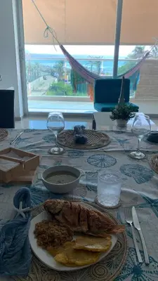 a table with a plate of food and wine glasses at SUNSET LATITUDE, Apto frente al mar con hamaca y piscina in Puerto Colombia