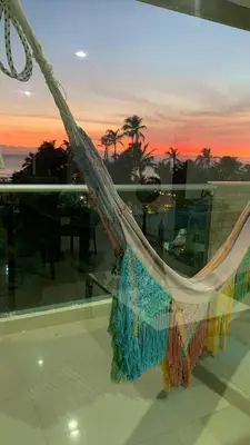 a hammock in a room with a view of the sunset at SUNSET LATITUDE, Apto frente al mar con hamaca y piscina in Puerto Colombia