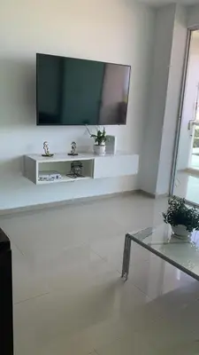 a living room with a flat screen tv on a white wall at SUNSET LATITUDE, Apto frente al mar con hamaca y piscina in Puerto Colombia