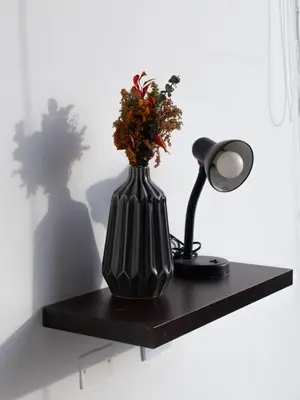 a black vase with flowers and a lamp on a shelf at SUNSET LATITUDE, Apto frente al mar con hamaca y piscina in Puerto Colombia