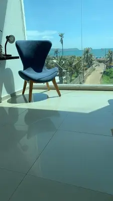 a blue chair sitting in front of a window at SUNSET LATITUDE, Apto frente al mar con hamaca y piscina in Puerto Colombia
