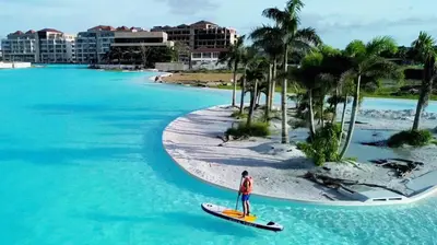 a person on a surfboard in the water near a beach at Baia Kristal Kabo Apartamento in Cartagena de Indias